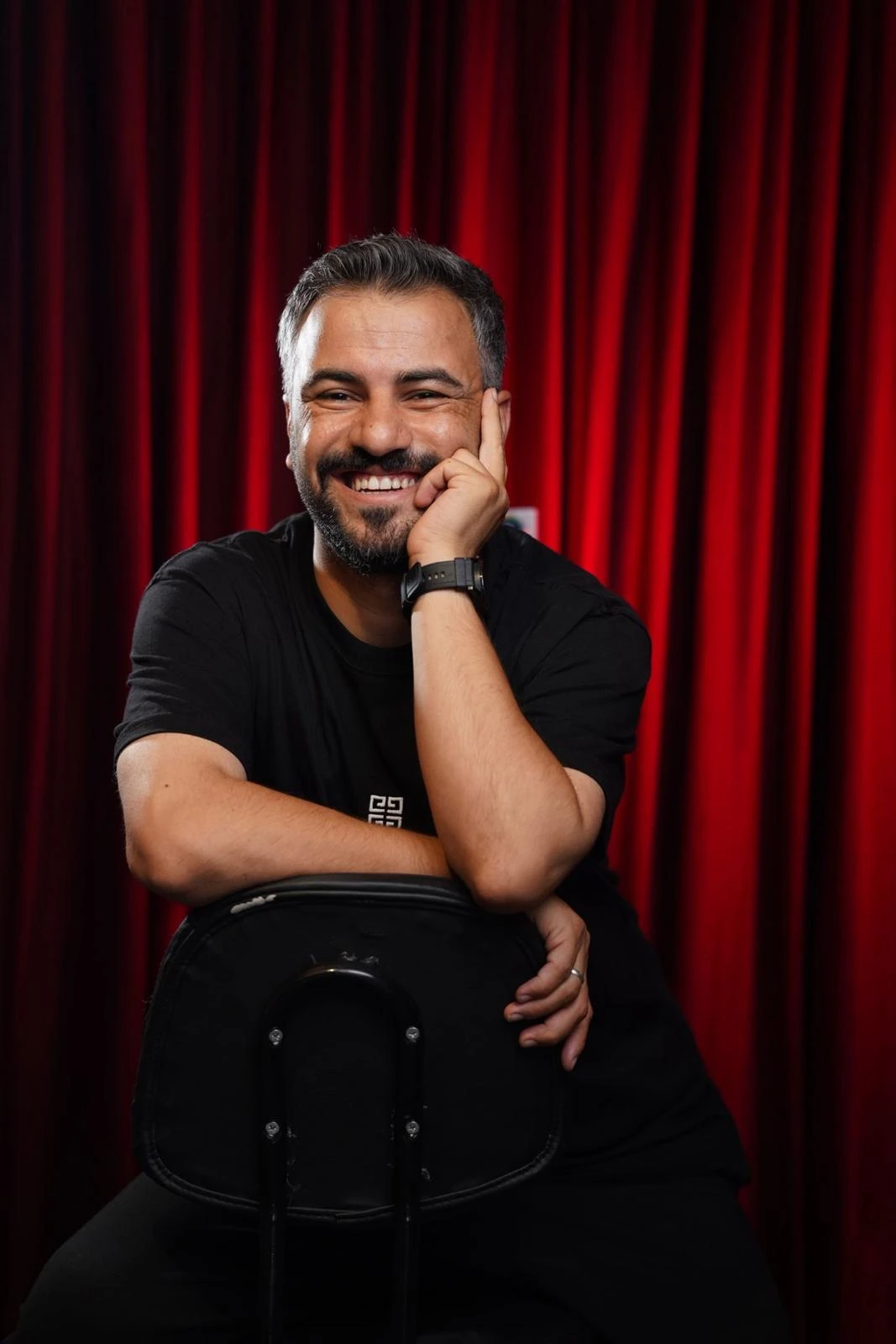 Kırmızı tiyatro perdesi önünde Fatih Sancaklı